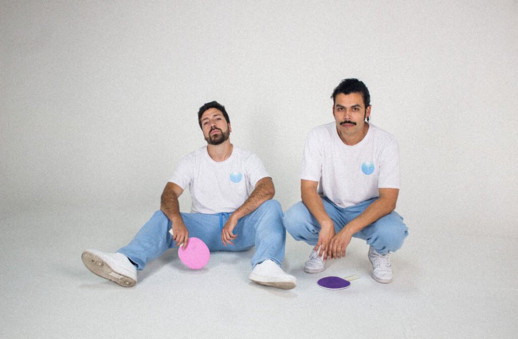 El dúo chileno Akinorite en el videoclip de “Fotos”, primer sencillo de su álbum PingPong. Una puesta en escena minimalista con patinadoras, luces de neón y estética retrofuturista que refuerza el concepto lúdico y nostálgico del disco.El dúo chileno Akinorite en el videoclip de “Fotos”, primer sencillo de su álbum PingPong. Una puesta en escena minimalista con patinadoras, luces de neón y estética retrofuturista que refuerza el concepto lúdico y nostálgico del disco.